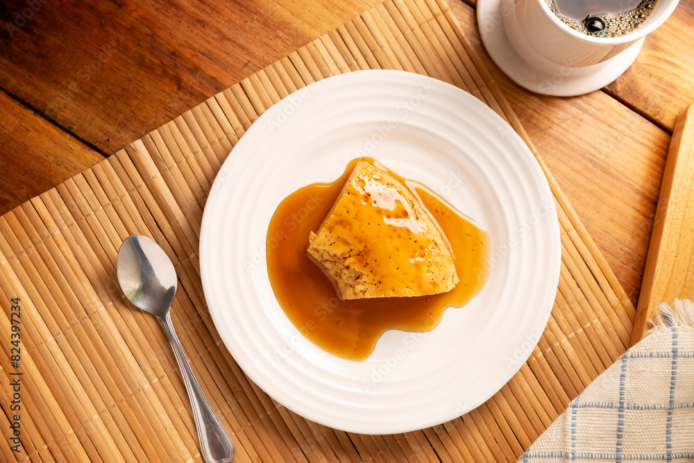 homemade flan dessert, also known as creme caramel, caramel custard pudding or egg custard, served on white plate on wooden table. homemade flan dessert, also known as creme caramel, caramel custard pudding or egg custard, served on white plate on wooden table.