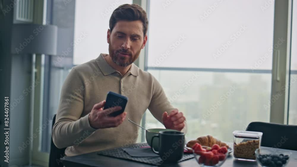 Eating guy receiving cellphone sms at panoramic kitchen closeup. Excited winner Eating guy receiving cellphone sms at panoramic kitchen closeup. Excited winner