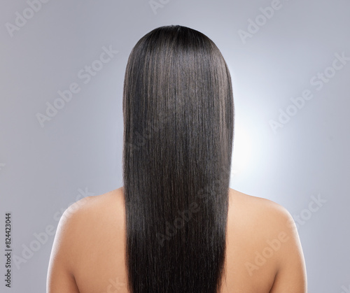 Hair care, beauty and back of woman in studio with natural, clean and salon treatment for wellness. Cosmetics, grooming and female person with long, glossy and shiny hairstyle by gray background.