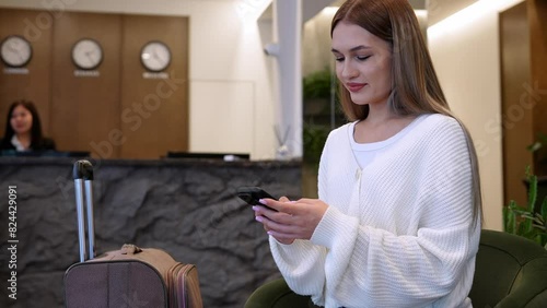 Stylish tripper texting in modern hotel lobby during evening check-in