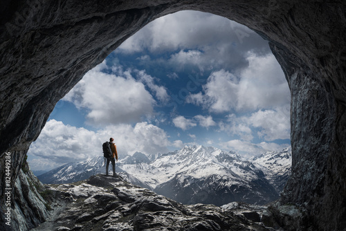 Wanderer in winterlichen Bergpanorama vor einer Höhle photo