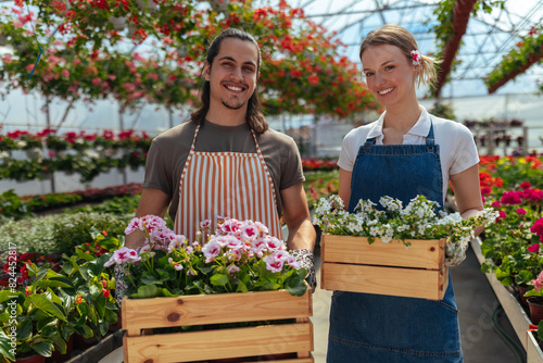 Two gardeners with crates of colorful flowers