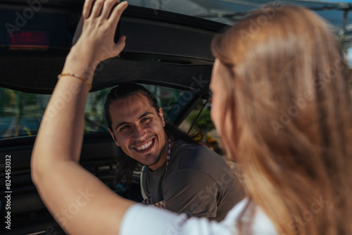 Smiling customers closes trunk with nursery worker