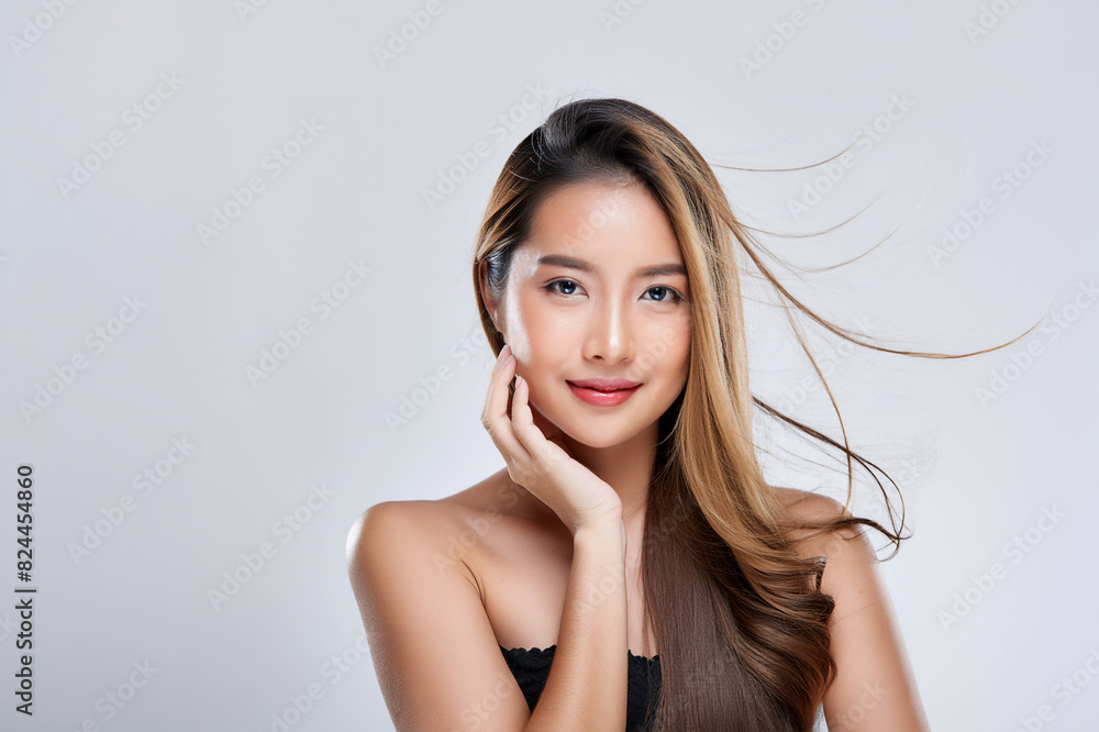 Beautiful young asian woman with long, blonde hair, blowing in the breeze, touching the side of her face with her hand. Beauty or skin care concept. Beautiful young asian woman with long, blonde hair, blowing in the breeze, touching the side of her face with her hand. Beauty or skin care concept.