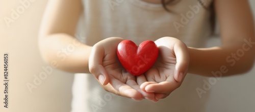 woman's hand holding a red heart shape concept of expressing love and affection photo