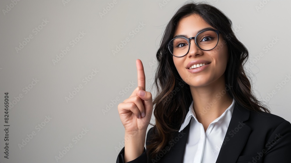 Young woman one finger pointing up happy surprised excited brunette female in suit spectacles eyeglasses copy space Young woman one finger pointing up happy surprised excited brunette female in suit spectacles eyeglasses copy space