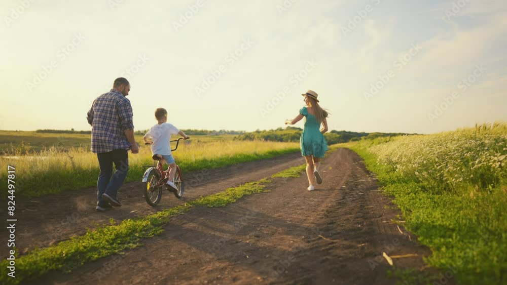 Childhood bike concept. Mother and dad teaching son to ride bicycle. Young family teaching son to ride bike first time on countryside rural road at sunset. Happy kid concept. The best moments together Childhood bike concept. Mother and dad teaching son to ride bicycle. Young family teaching son to ride bike first time on countryside rural road at sunset. Happy kid concept. The best moments together