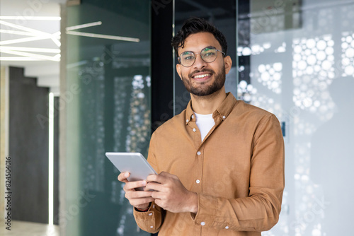 Quadro su tela Smiling young professional using tablet in modern office environment