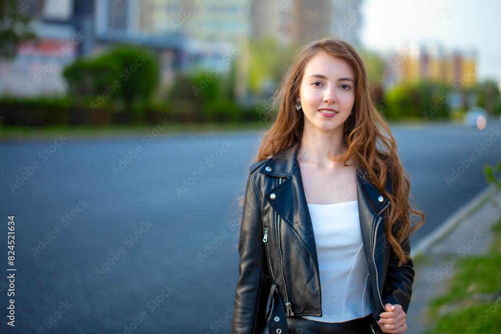 A young smiling girl in a good mood walks around the city. Teenage girl, portrait against the background of houses and roads. Fashionable youth style trend. A young smiling girl in a good mood walks around the city. Teenage girl, portrait against the background of houses and roads. Fashionable youth style trend.