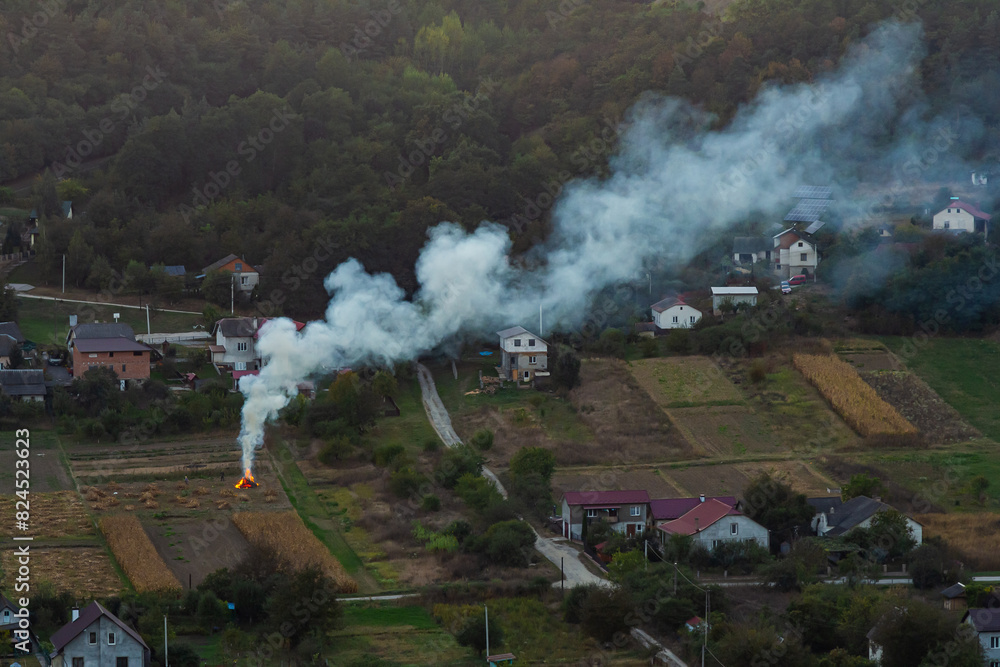 Fototapeta premium agricultural waste bonfires from dry grass and straw stubble burning with thick smoke polluting air during dry season causing global warming and carcinogen fumes
