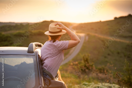 Girl with hat in the window of the car. Adventure, vacation, road trip concept.