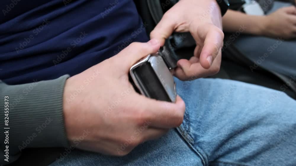 A man passenger unfastens the seatbelt on the airplane after takeoff and landing. A person unbuckled or unlocked buckle the seat belt on the plane. Concept of safe traveling by air. Safety rules. 4K A man passenger unfastens the seatbelt on the airplane after takeoff and landing. A person unbuckled or unlocked buckle the seat belt on the plane. Concept of safe traveling by air. Safety rules. 4K