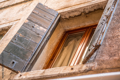 Window with brown shutters on the window sill in Italy.