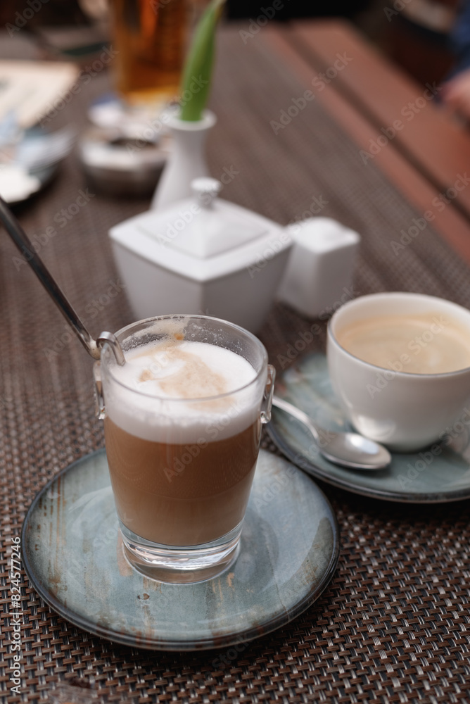 Two cups of cappuccino with latte art on wooden background. Beautiful foam, greenery ceramic cups, stylish toning Two cups of cappuccino with latte art on wooden background. Beautiful foam, greenery ceramic cups, stylish toning