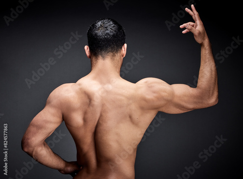 Muscular man, back and fitness with muscle for strength, workout or exercise in studio on a black background. Rear view of male person, bodybuilder or strong model with bicep, shoulder or deltoid photo