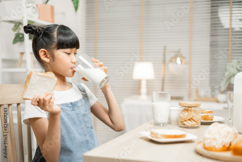 Asian family enjoying a nutritious breakfast at home, with their daughter holding a glass of milk.