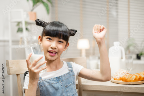 Asian family enjoying a nutritious breakfast at home, with their daughter holding a glass of milk.