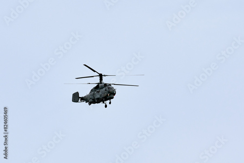 Russian military helicopter armed with missiles flies in blue sky, airborne mission of gunship with targeting system performs an aerial maneuvers for military operation, russian aviation
