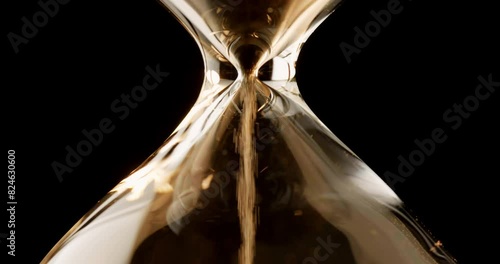 Closeup of sand timer clock with sand flowing from through hourglass on white background.
