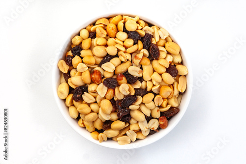 Flat lay, top view of Peanut and raisin mix in round white bowl, isolated on white.