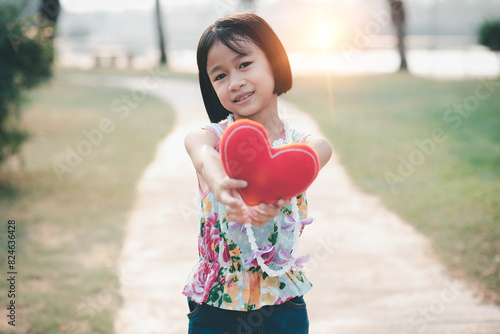 happy little girl holding a red heart-shaped toy on valentine's day