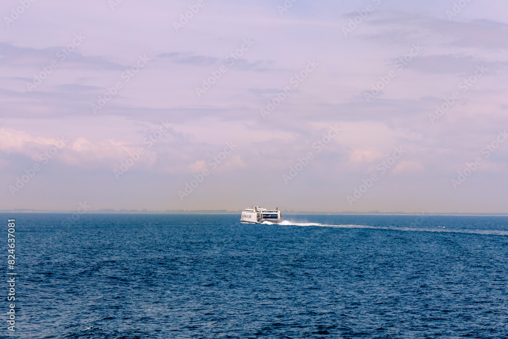 Seascape with a white ferry in the distance and waves.