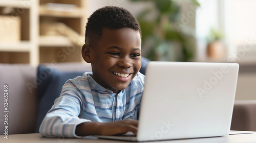 smiling boy using a laptop computer on a table in a living room © Free Studio