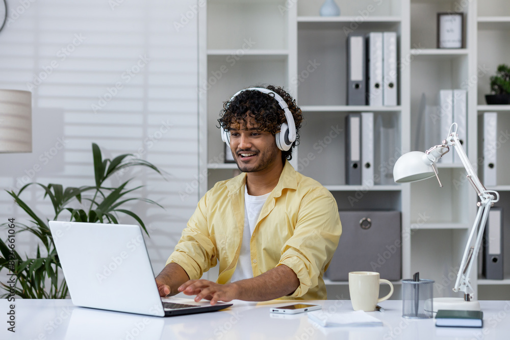 Man working remotely with laptop and headphones in modern home office Man working remotely with laptop and headphones in modern home office