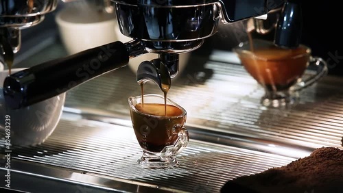 Close-up of the Espresso coffee extraction from a professional coffee machine with a bottomless filter. Coffee flowing into cup. Coffee aroma and the warm shop atmosphere photo