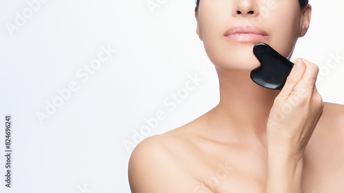 Woman Using Gua Sha Stone for Facial Skincare Routine. Cropped portrait on white background with copy space