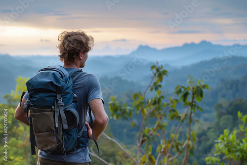 A handsome man carrying backpack and camera standing on the top of mountain with beautiful nature view background, back shot, copy space concept.