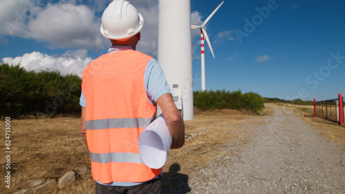 engineer walks along road in a field of wind turbines