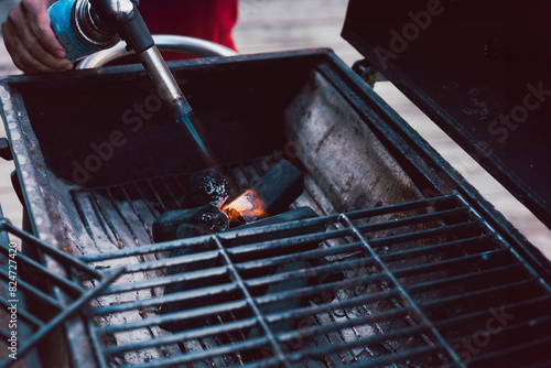 Man using BBQ lighter torch to start fire for charcoal.