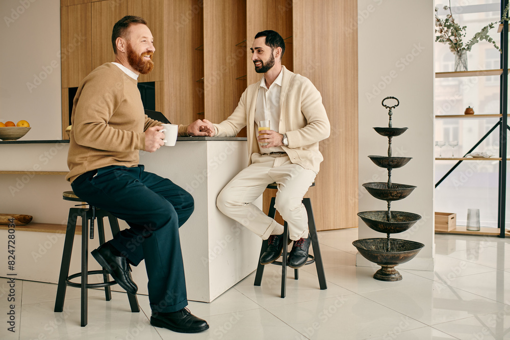 Two men, a happy gay couple, engage in conversation while seated on stools in a modern kitchen. Two men, a happy gay couple, engage in conversation while seated on stools in a modern kitchen.