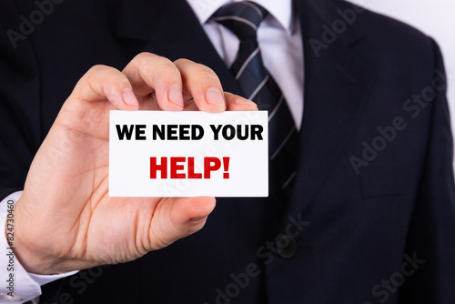 Businessman holding a card with text We need your help