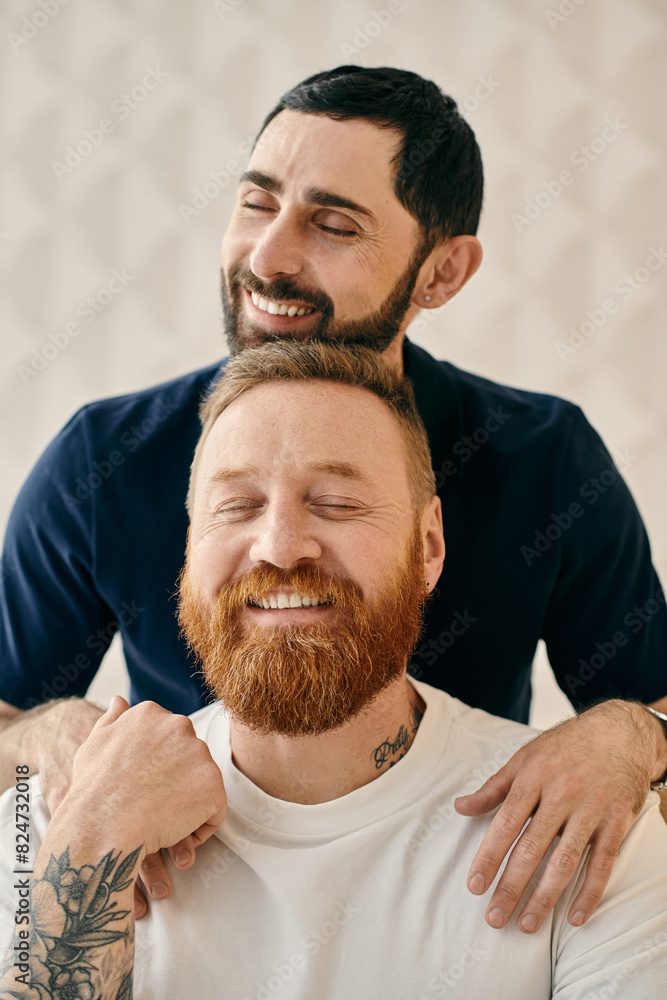 Fototapeta premium A happy gay couple, one with a red beard, sharing a warm hug in a cozy modern living room.