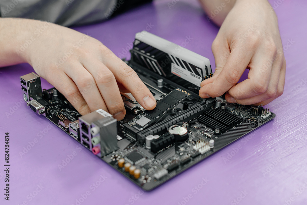 system administrator installing SSD into motherboard, assembling PC of different accessories or components, close-up view of hands, computer repair and maintenance concept system administrator installing SSD into motherboard, assembling PC of different accessories or components, close-up view of hands, computer repair and maintenance concept