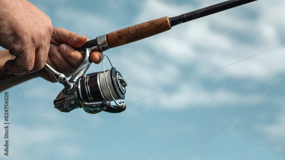 Freshwater fishing in summer. Spinning reel on a spinning rod in the hands of a fisherman. Freshwater fishing in summer. Spinning reel on a spinning rod in the hands of a fisherman.