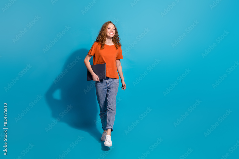 Photo of positive smiling girl hold netbook look profile side isolated blue color background Photo of positive smiling girl hold netbook look profile side isolated blue color background