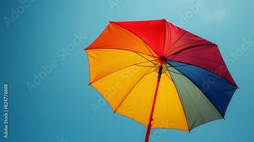 A serene image of a rainbow-colored umbrella against a clear blue sky  symbolizing protection and support for the LGBTQ  community. List of Art Media Photograph inspired by Spring magazine