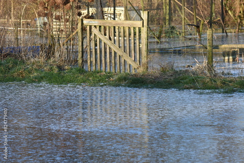 gate of  a vegetable garden reflected in the frozen high water 
