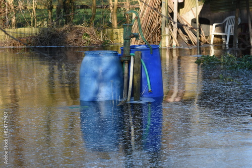 pump and water barrels in the high water of the vegetable gardens that is frozen