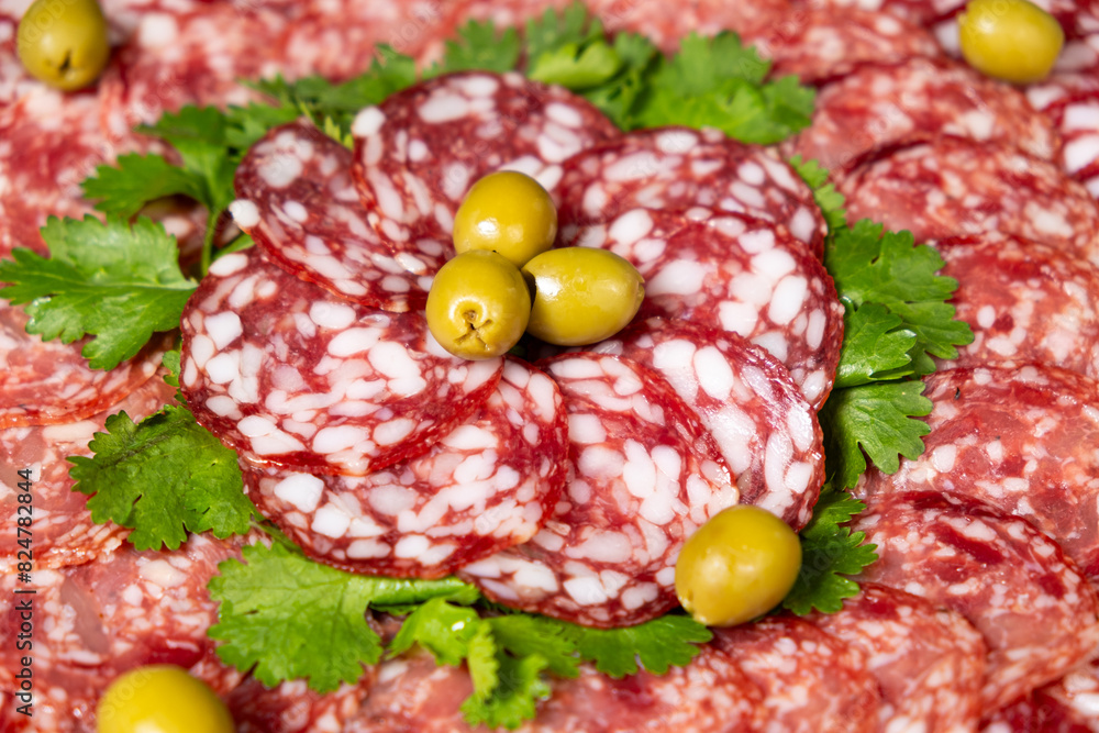 Thinly sliced smoked salami sausage with cilantro and olives Thinly sliced smoked salami sausage with cilantro and olives