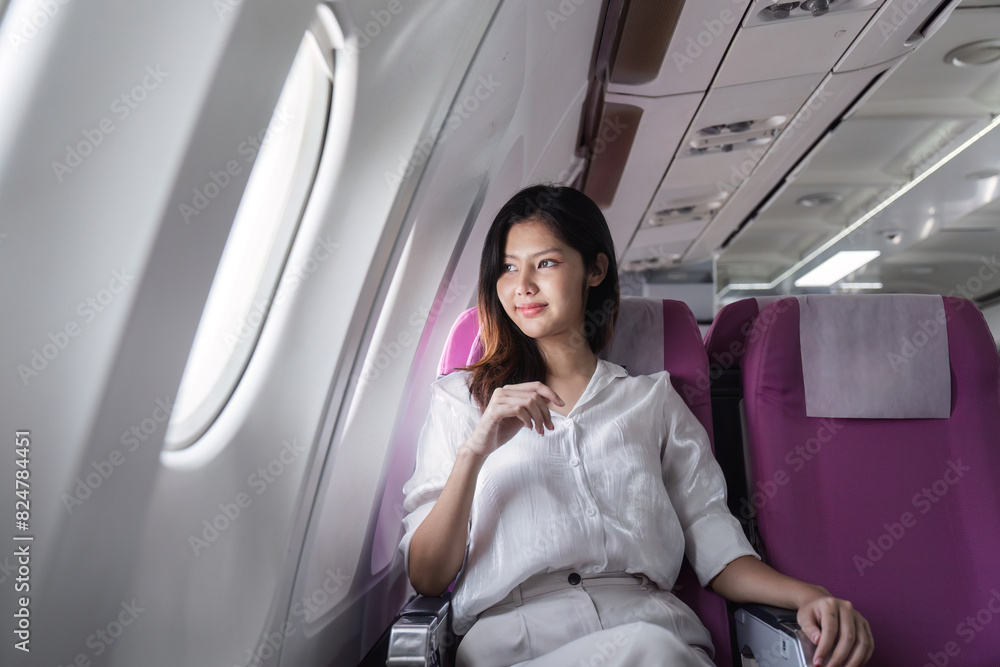 Fototapeta premium Businesswoman smiling while sitting in airplane seat. Concept of business travel and professional journey