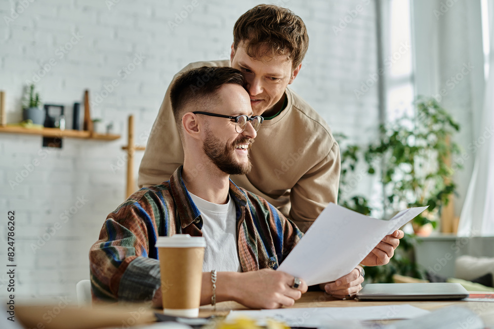 Two men sitting at table, examining paper, discussing designs for trendy attire. Two men sitting at table, examining paper, discussing designs for trendy attire.