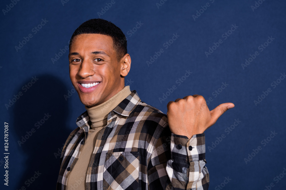 Photo portrait of nice young man point empty space wear trendy plaid outfit isolated on dark blue color background Photo portrait of nice young man point empty space wear trendy plaid outfit isolated on dark blue color background