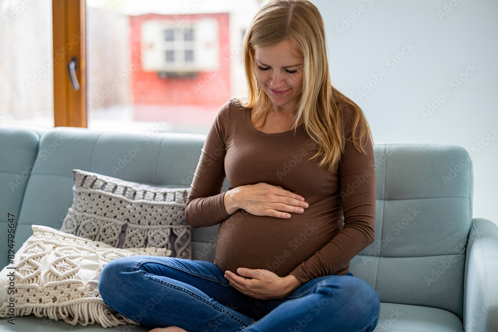 Pregnant woman touching her belly, relaxing on sofa at home
Pregnant woman touching her belly, relaxing on sofa at home