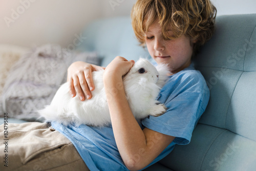 Cute little boy cuddling his bunny pet at home
