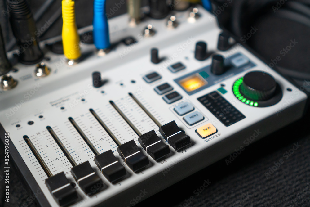 Close-up image of hand adjusting mixer knob for volume control during live studio performance. Mixer features multiple knobs and buttons for precise audio mix adjustments.