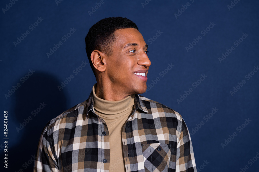 Photo portrait of attractive young man look empty space dressed stylish checkered clothes isolated on dark blue color background Photo portrait of attractive young man look empty space dressed stylish checkered clothes isolated on dark blue color background
